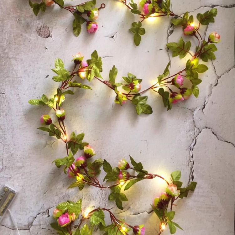 Window sill decorated with pink rose bud garland lights creating pastoral nature scenery