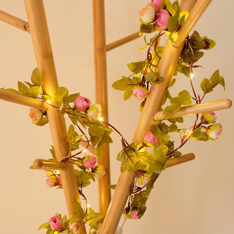 Romantic bedroom headboard draped with pink rose bud garland fairy lights creating enchanting ambiance